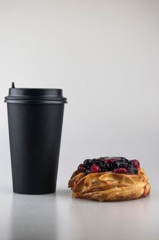 Delicious berries pastries with paper disposable coffee cup on a white background. Breakfast