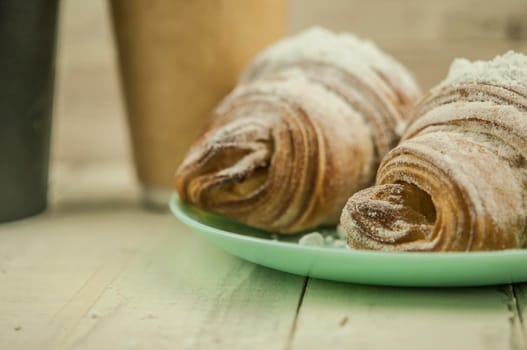 Two fresh croissants in plate on white wooden table. Breakfast