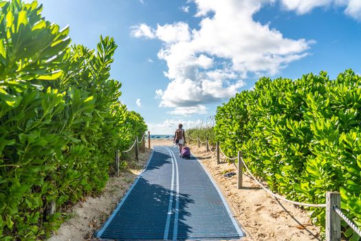 Woman walking to the beach on Footpath. South Beach in Miami, Florida, USA