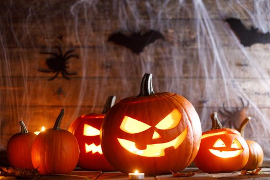 Halloween, decorations and holidays concept - pumpkins with bats, spider web and candles