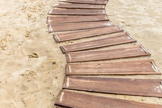 Wooden beach boardwalk, path with sand with copy space