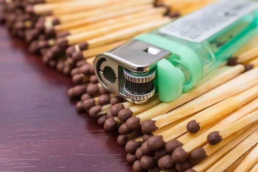 A gas pocket lighter lies on a stack of matches close-up