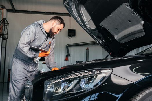 Car mechanic working with laptop in Auto Repair Service