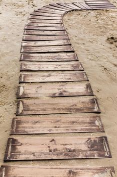 Wooden beach boardwalk, path with sand with copy space