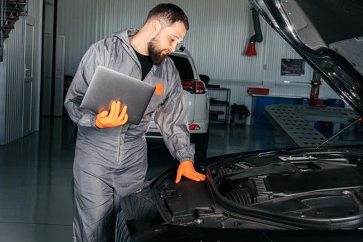 Car mechanic working with laptop in Auto Repair Service