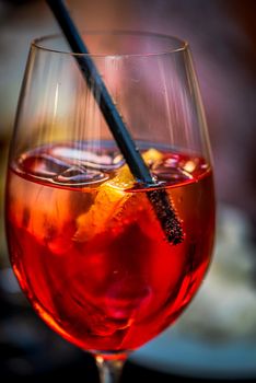 Fresh red cocktail with ice cubes and a straw, close-up photo of light alcoholic drink