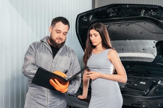 Auto Mechanic explains vehicle repair invoice to a female customer and signing papers