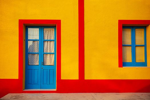 View of a typical colorful house of Linosa, colored red and yellow with blue door and window