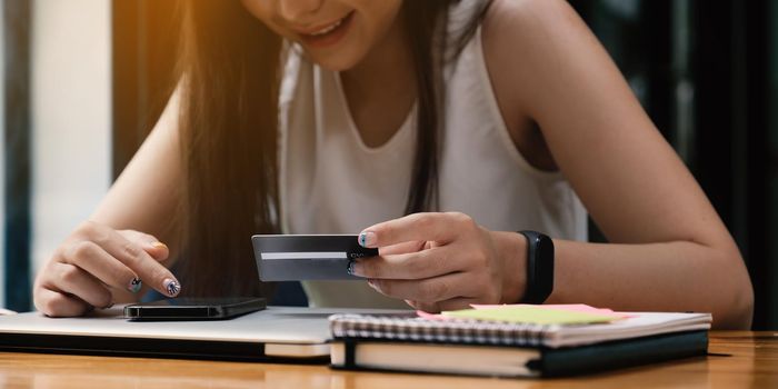 Woman enjoy with online shopping application and looking at credit card for fill number to payment.