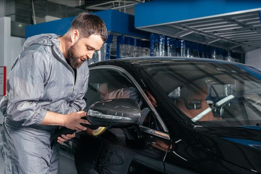 Worker polishing vehicle body with special grinder and wax from scratches at the car service station