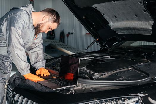 Car mechanic working with laptop in Auto Repair Service