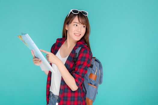 Beautiful happy young asian woman travel looking and pointing a paper map isolated on blue background, asia girl search journey with direction in vacation trip with cheerful for leisure.