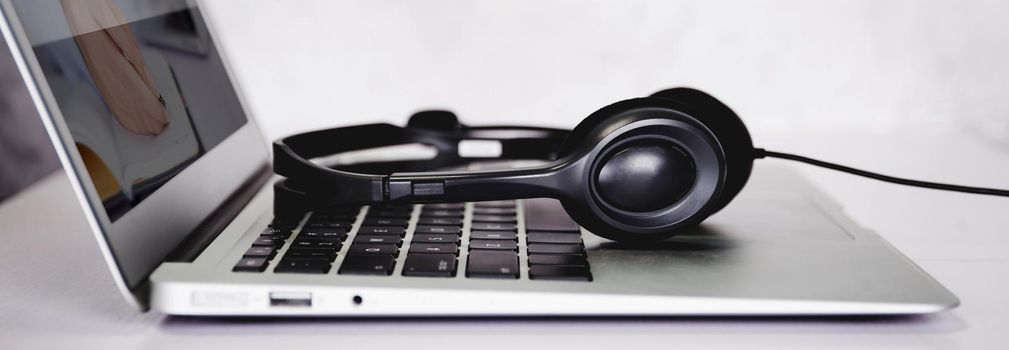 Laptop computer and headphone on desk, e-learning online, webinar for education and learning, seminar with notebook, video conference, headset for multimedia, course and classroom to internet.