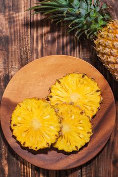 Fresh sliced pineapple on a wooden background.