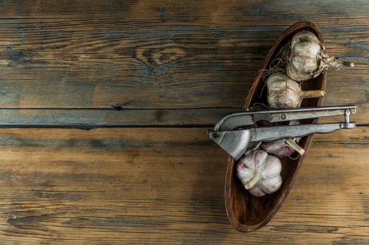 Organic garlic with metal press. Fresh garlic cloves and garlic bulb on a wooden table. Garlic for healthy eating. Concept of spices for healthy cooking. Top view