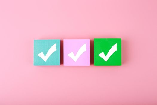 Three checkmarks top view on bright pastel pink background with copy space. Concept of questionary, checklist, to do list, planning, business or verification. 