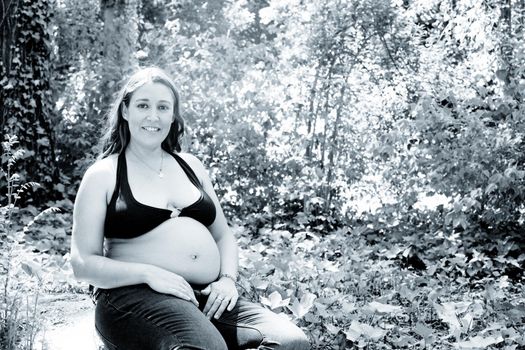 Seven month pregnant woman in a park dressed in jeans