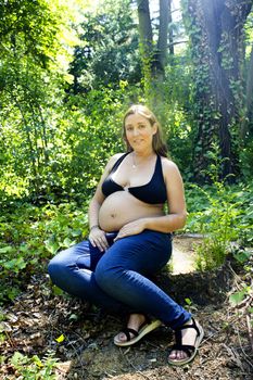 Seven month pregnant woman in a park dressed in jeans