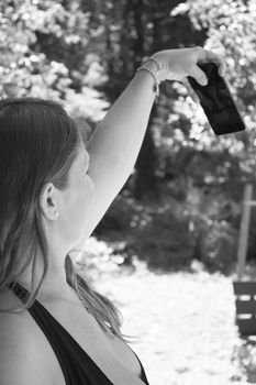 Seven month pregnant woman taking a selfie in a park