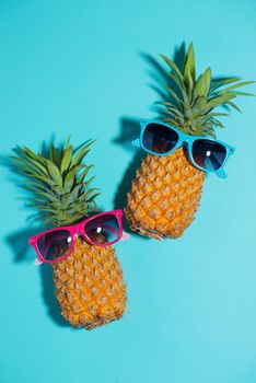 Funny pineapple in a sunglasses over blue background