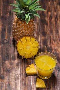 Fresh pineapple juice in the glass with pineapple fruit on wooden background.