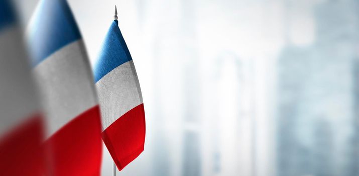 Small flags of France on a blurry background of the city.