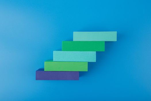 Ladder of success modern and trendy business or personal development concept. Top view of ladder made of multicolored rectangles with space for text against blue background