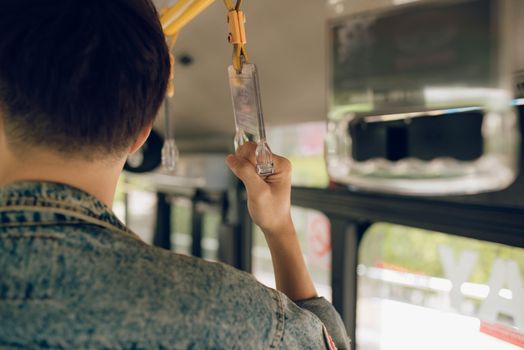 Male hand holding onto a handle of bus