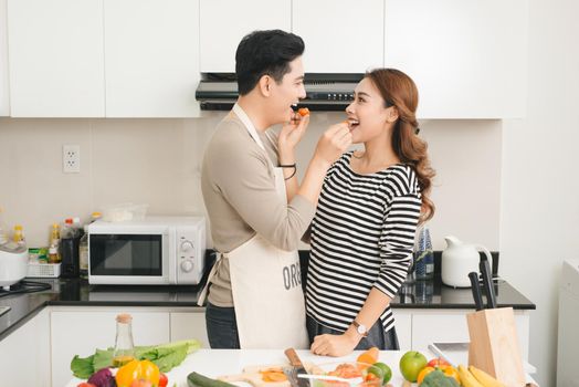 Loving Vietnamese couple cooking together in the kitchen at home