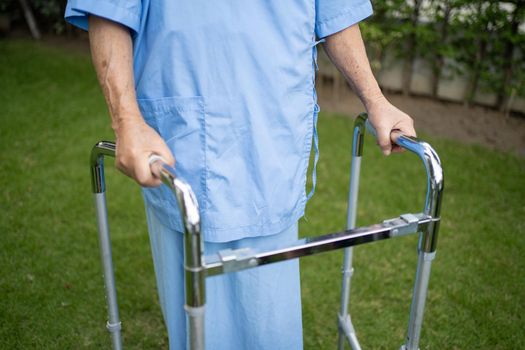 Asian senior or elderly old lady woman use walker with strong health while walking at park in happy fresh holiday.