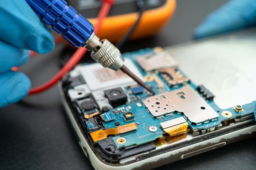 Technician repairing inside of mobile phone by soldering iron. Integrated Circuit. the concept of data, hardware, technology.