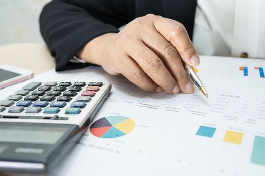 Asian accountant working and analyzing financial reports project accounting with chart graph and calculator in modern office, finance and business concept.