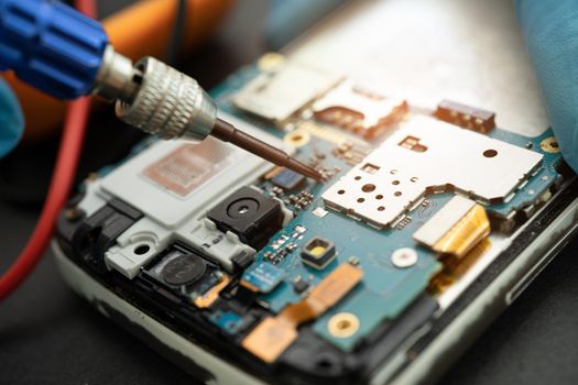 Technician repairing inside of mobile phone by soldering iron. Integrated Circuit. the concept of data, hardware, technology.