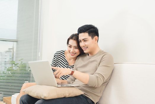 Young asian couple surfing on internet with laptop.