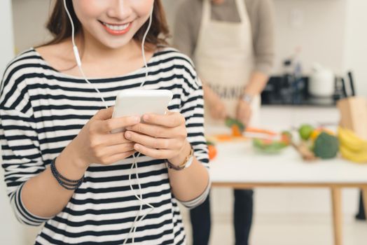 Smiling asian woman in the kitchen writing text message