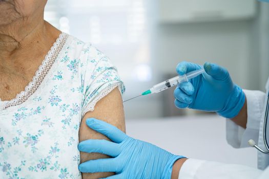 Elderly Asian senior woman wearing face mask getting covid-19 or coronavirus vaccine by doctor make injection.