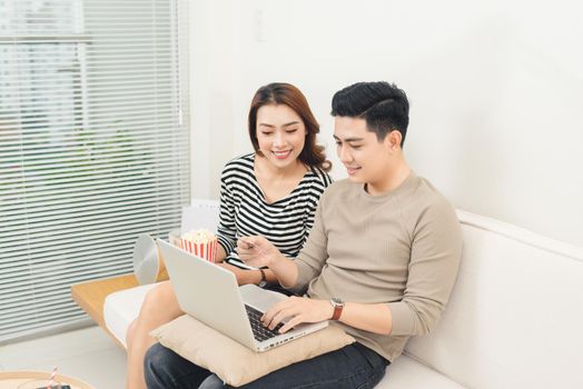 Young asian couple payment online using laptop buying movie ticket