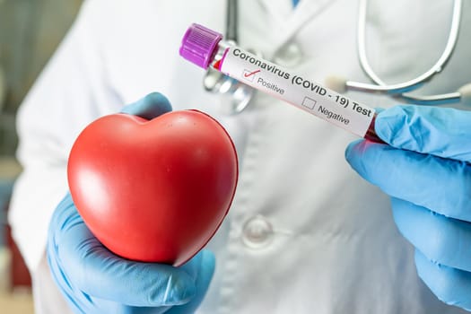 Positive blood infection sample in test tube for covid-19 coronavirus in lab. Scientist holding red heart to encourage patient in hospital.