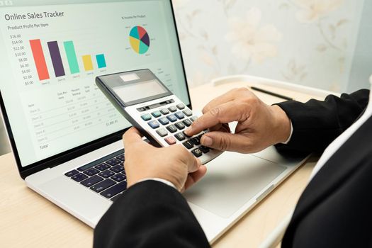 Asian accountant working and analyzing financial reports project accounting with chart graph and calculator in modern office, finance and business concept.