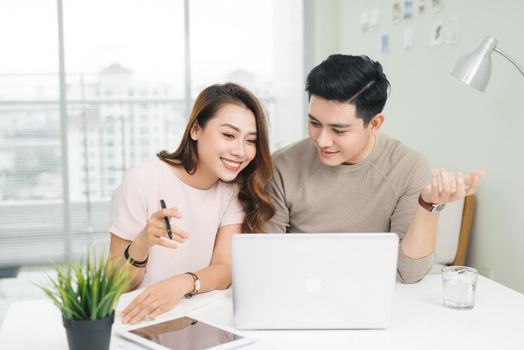 Happy businesswoman and businessman using laptop at workplace in office