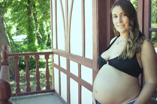 Seven months pregnant young woman dressed in black bikini and jeans