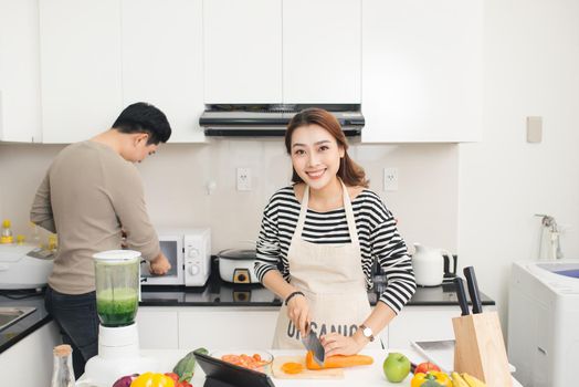 Asian couple, man and woman, cooking food together in kitchen