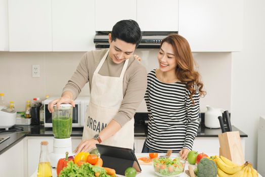 Portrait of happy asian young couple cooking together in the kitchen at home.