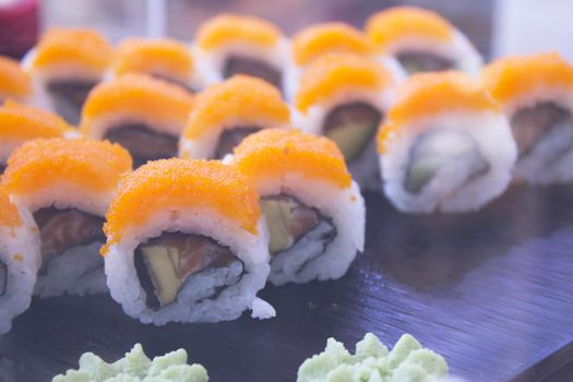 Assorted sushi food on a black slate plate. No people