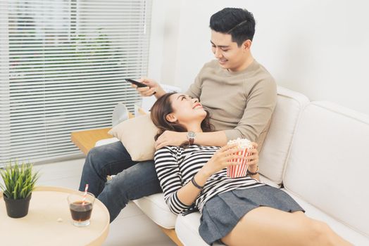 Young couple with popcorn on the sofa watching a movie