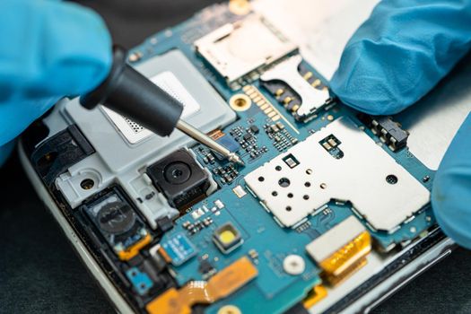 Technician repairing inside of mobile phone by soldering iron. Integrated Circuit. the concept of data, hardware, technology.