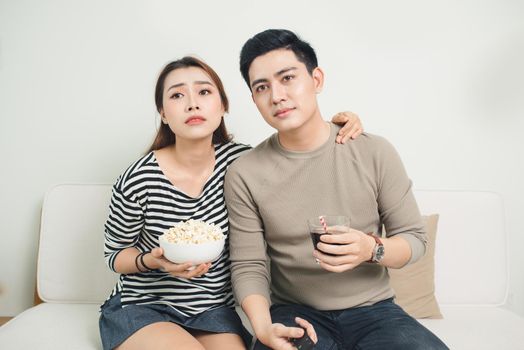 Bored young couple watching television at home