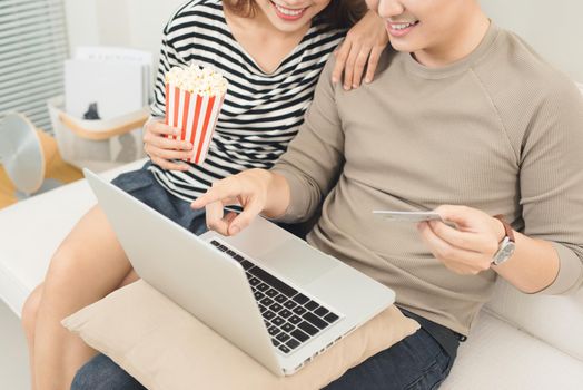 Young asian couple payment online using laptop buying movie ticket