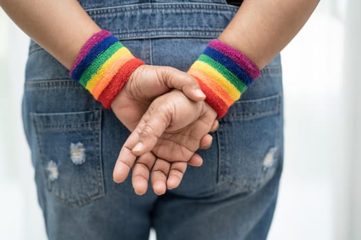 Asian lady wearing rainbow flag wristbands, symbol of LGBT pride month celebrate annual in June social of gay, lesbian, bisexual, transgender, human rights.