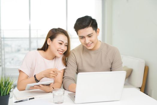 Happy businesswoman and businessman using laptop at workplace in office